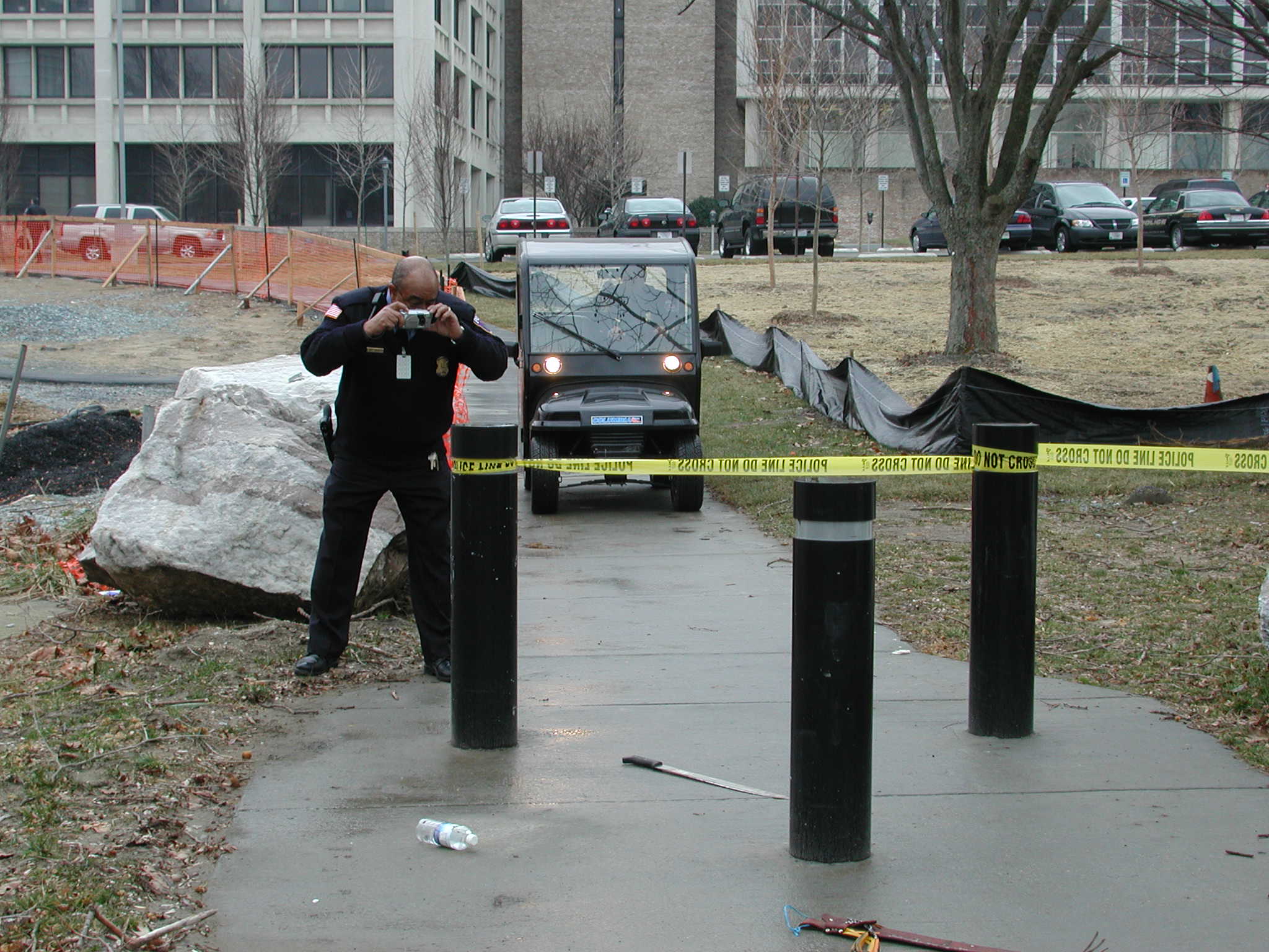 Outdoor crime scene officer taking a phot and police cart arriving 2.JPG