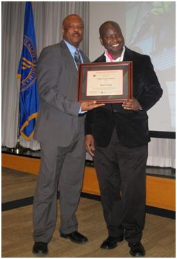 Two men standing up, holding an award